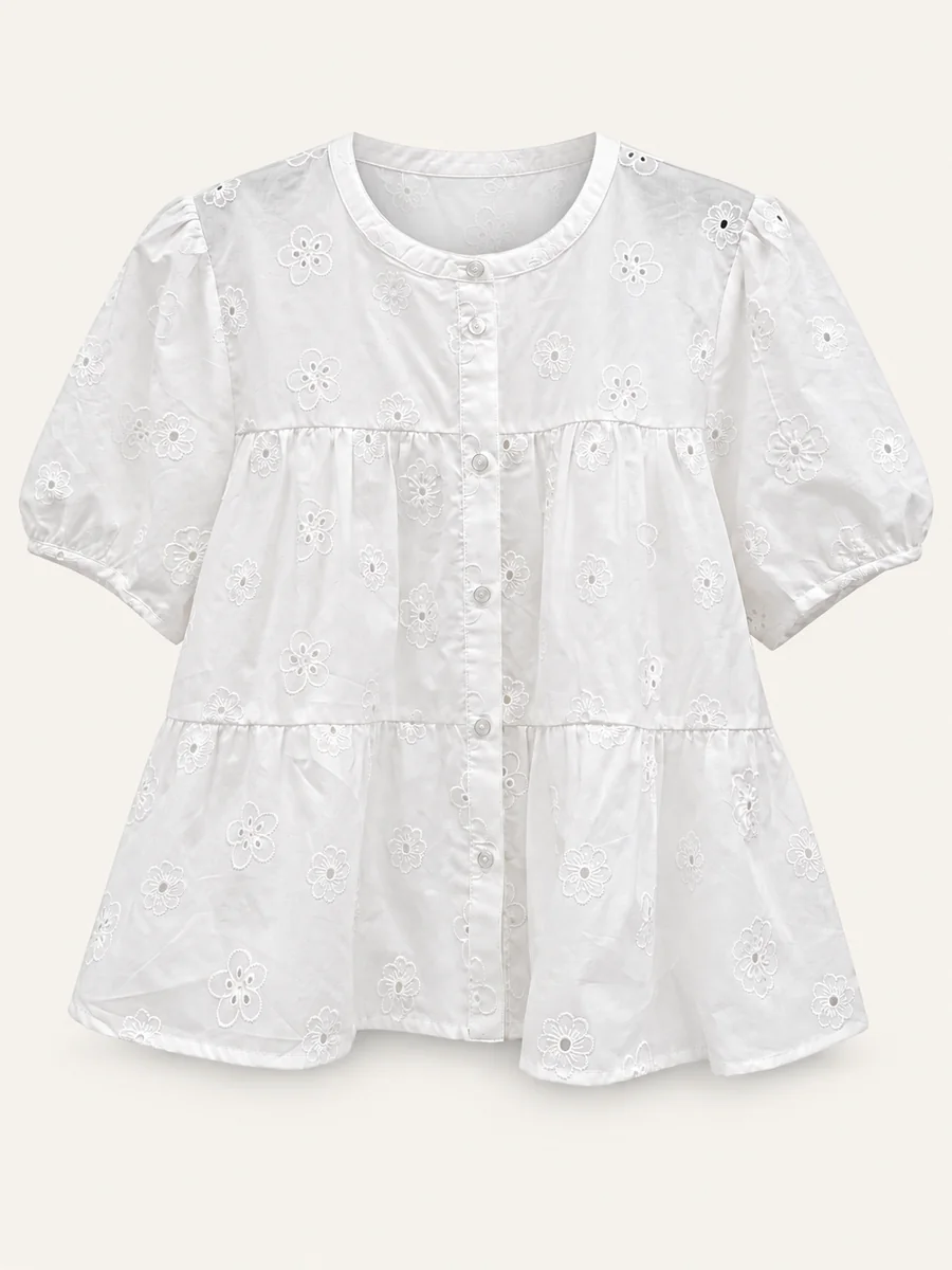 White short-sleeve embroidered tiered blouse on a warm off-white background